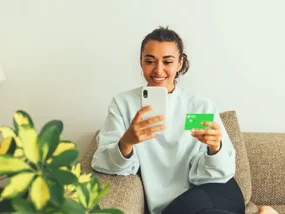 Women checking phone while holding debit card