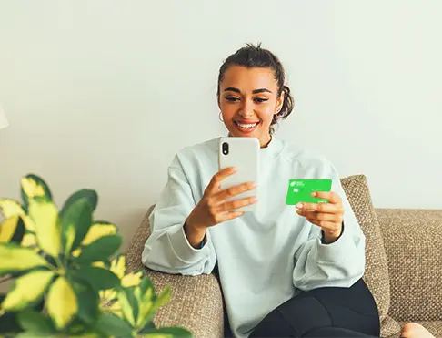 Women checking phone while holding debit card