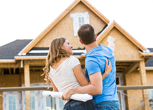 Couple in front of new home under construction