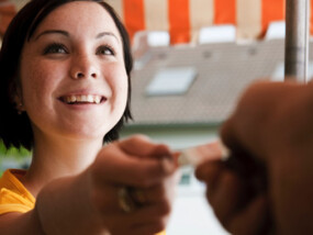 Young woman handing a merchant her credit card.