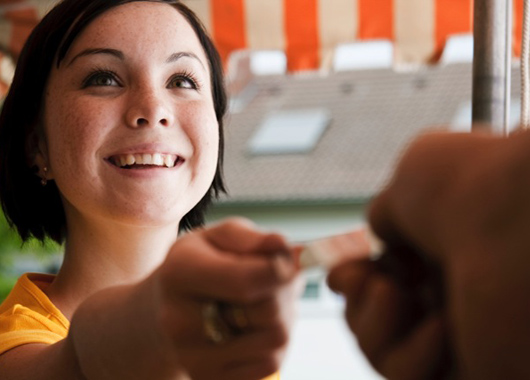 Young woman handing a merchant her credit card.