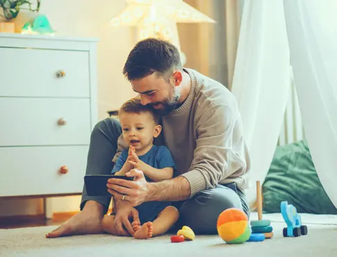 Dad and toddler son looking at smart phone