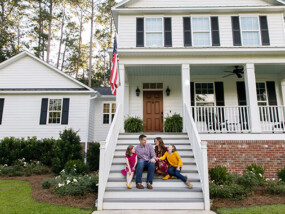 Family in front of white home.