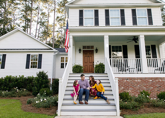 Family in front of white home.