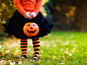 Little girl in witch costume playing in autumn park. Child having fun at Halloween trick or treat. Kids trick or treating. Toddler kid with jack-o-lantern. Children with candy bucket in fall forest.