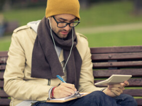 Young man sitting on a park bench reviewing his finances.