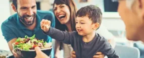 Family laughing while eating dinner