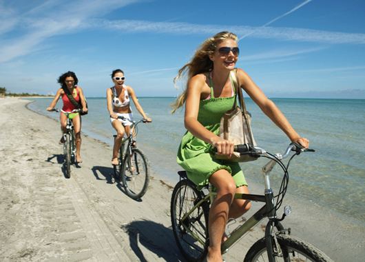 Three young women riding bicycles on beach