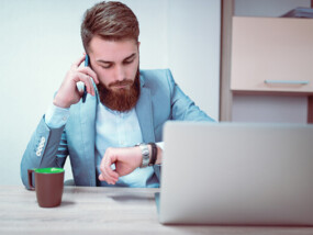 Businessman looking at watch while working on laptop.