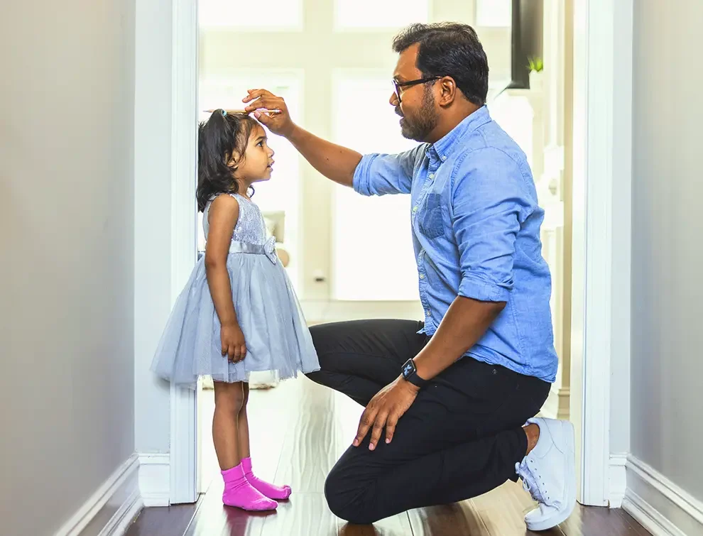 Dad measuring daughter in door frame of house