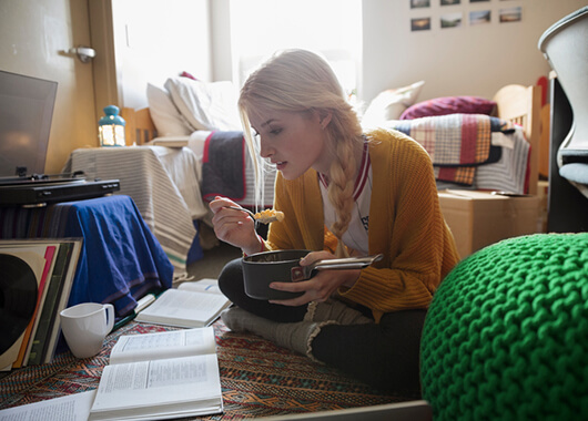 College student eating and studying in her room.