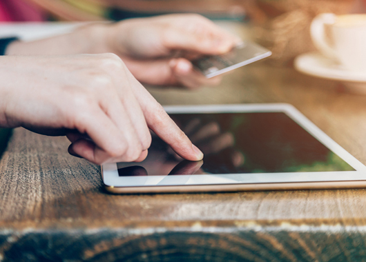 woman pays by credit card for online purchase on a tablet computer.