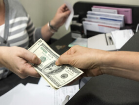 Teller and member exchanging money after transaction.