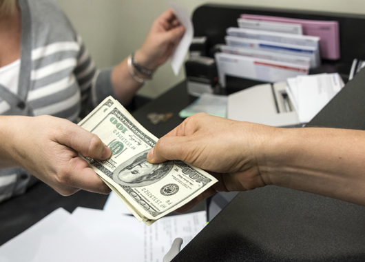 Teller and member exchanging money after transaction.