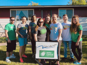 ICCU employees standing in front of the Paintfest sign and house.