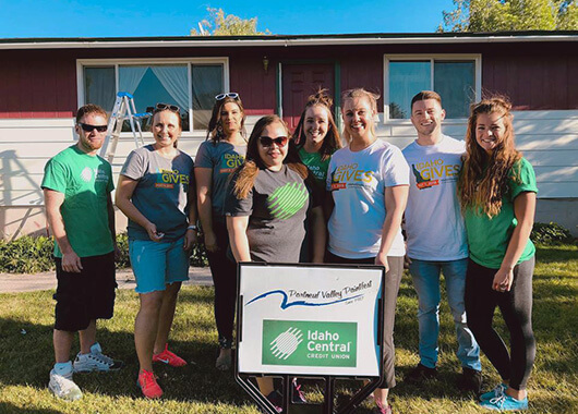 ICCU employees standing in front of the Paintfest sign and house.