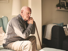 elderly man sitting in chair with cane