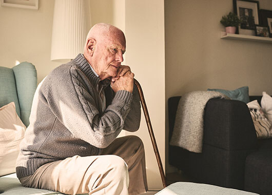 elderly man sitting in chair with cane