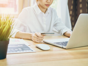 Woman shopping online using her debt card.