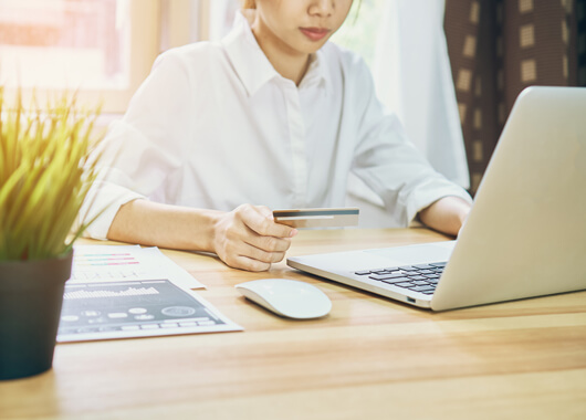 Woman shopping online using her debt card.