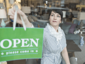 small business owner placing open sign in store window|New business owner checking her online banking on her tablet.