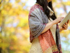 Woman on a tablet outside in autumn.