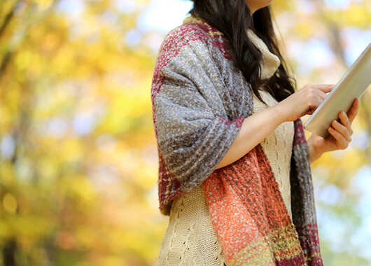 Woman on a tablet outside in autumn.