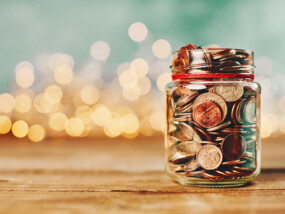 Jar of change with Christmas lights in the distance behind it.