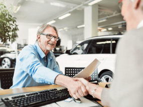 Man signing paperwork at car dealership.