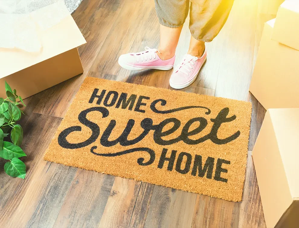 Women standing next to welcome home mat