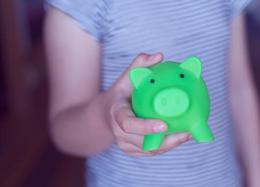 Kid holding a green piggy bank.