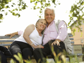 Happy retired couple sitting on a park bench.