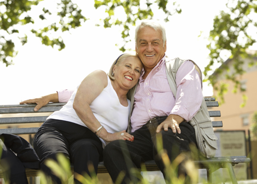 Happy retired couple sitting on a park bench.