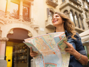 Girl holding a map outside of a building while she travels abroad.