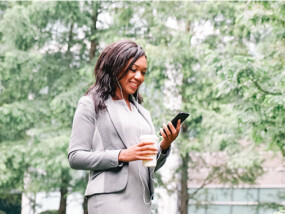 Woman employee talking on her cell phone outside with a headset.