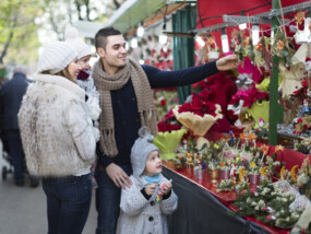 Smiling young parents with little girls at counter with Poinsettia. Focus on woman