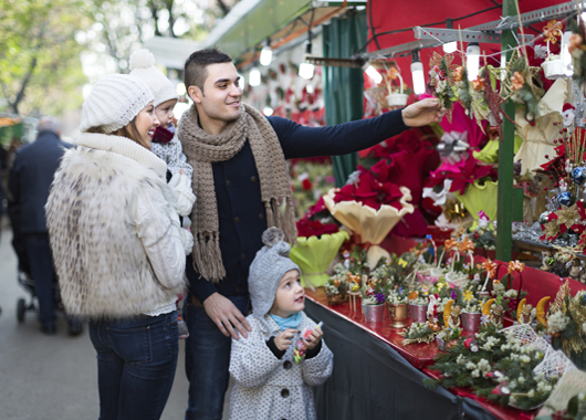 Smiling young parents with little girls at counter with Poinsettia. Focus on woman