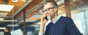 Man on talking on phone while browsing computer