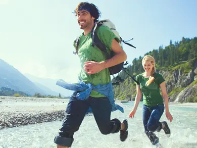 couple running through water on a hike