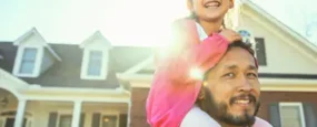 Dad with Daughter sitting on his shoulders smiling