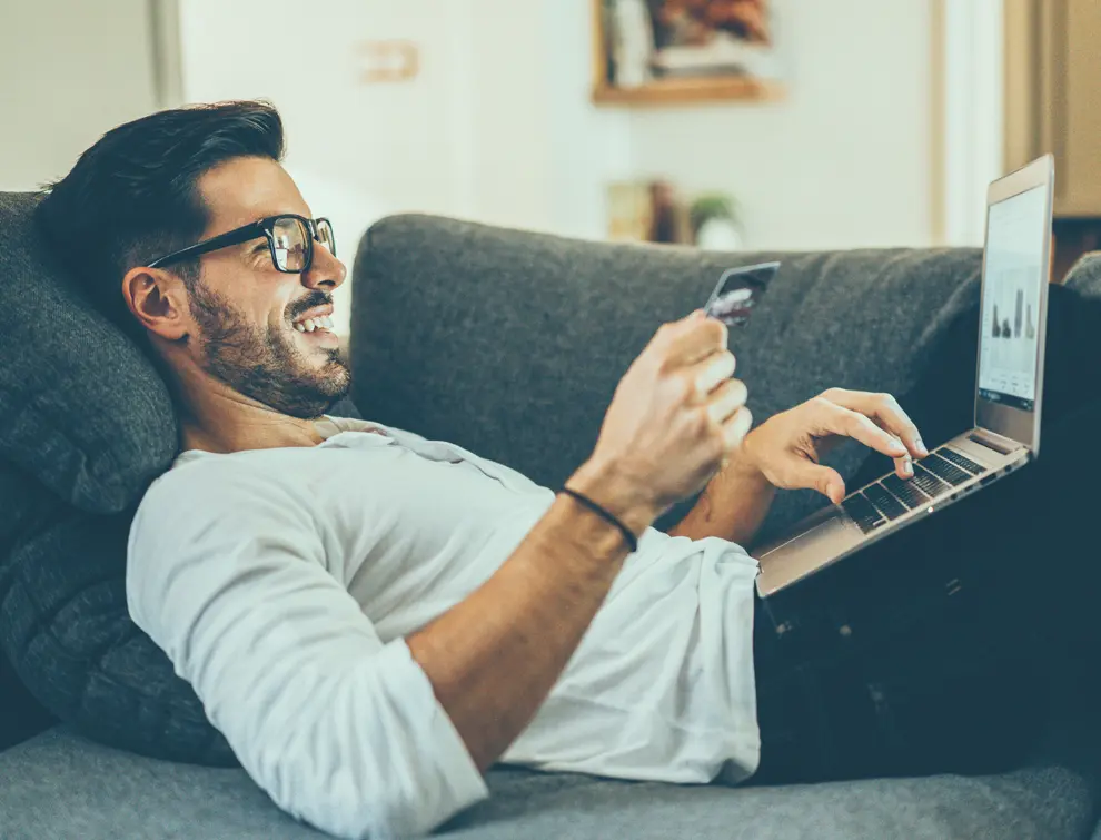 Man laying on couch holding his credit card