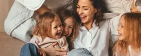 Mom playing under a blanket with her kids