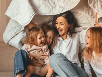 Mom playing under a blanket with her kids