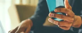 Man holding phone while browsing computer