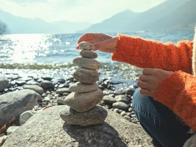 Someone stacking rocks with a lake behind them
