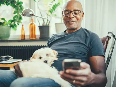 man with dog on his lap looking at his phone