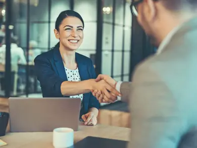 a women smiling while shaking hands with someone else