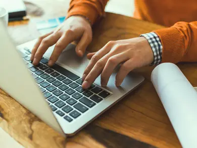 A persons hands typing on a computer