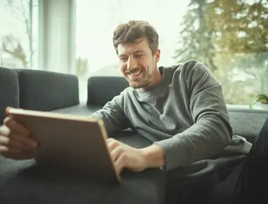man smiling while looking at tablet