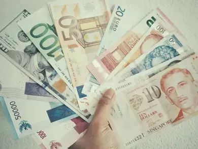 Multi-colored currencies from across different nations fanned out in one hand.